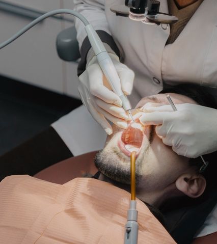 A dentist carrying out a dental procedure on a patient in the dental chair.